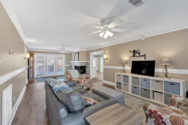 living room with ornamental molding, hardwood / wood-style floors, ceiling fan, and a fireplace