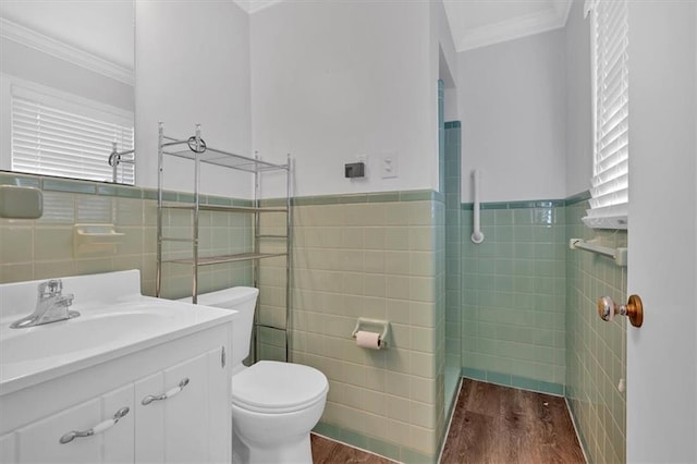 bathroom with ornamental molding, wood-type flooring, toilet, and tile walls