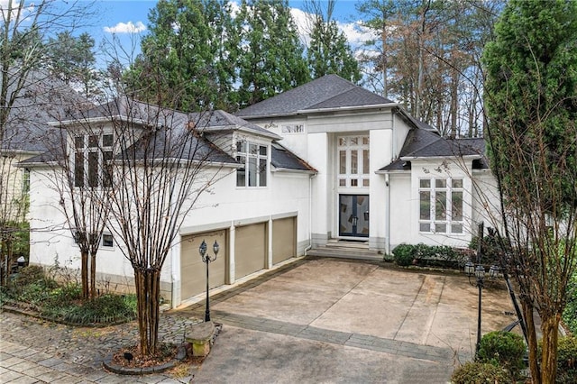 view of front of house with driveway, french doors, a shingled roof, and stucco siding