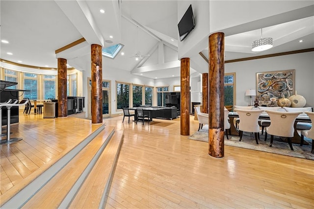 interior space with high vaulted ceiling, decorative columns, beamed ceiling, and light wood finished floors