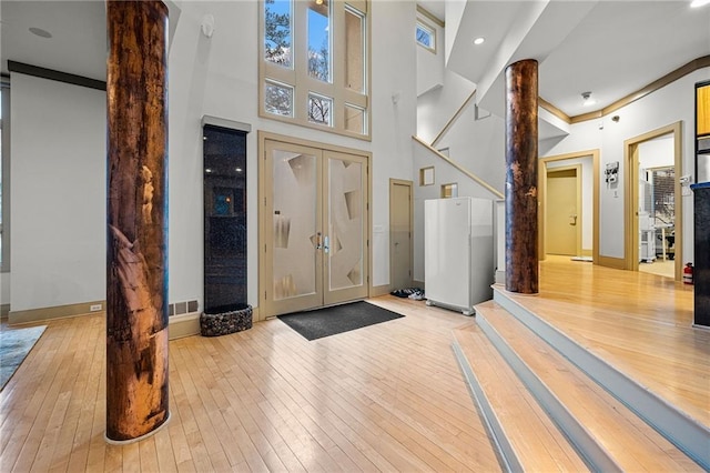 foyer entrance featuring ornate columns, visible vents, and hardwood / wood-style flooring