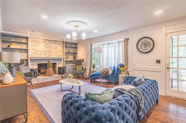 living room with built in features, dark hardwood / wood-style flooring, a brick fireplace, and a wealth of natural light