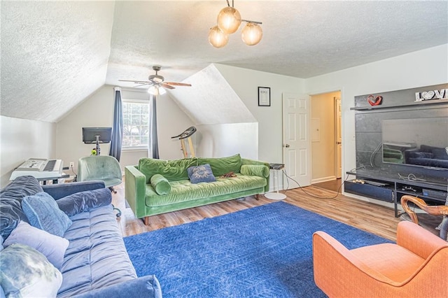 living room featuring vaulted ceiling, ceiling fan, wood-type flooring, and a textured ceiling