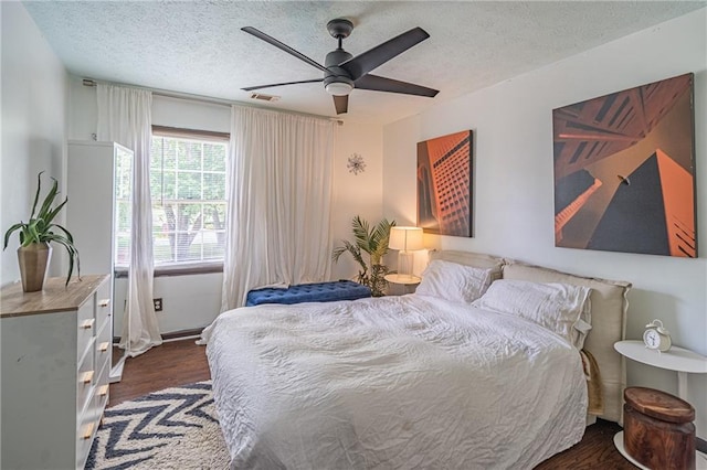 bedroom featuring a textured ceiling, ceiling fan, and dark hardwood / wood-style floors