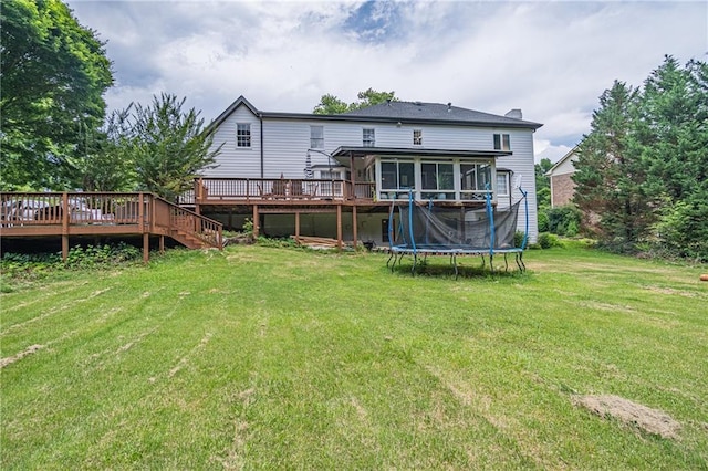 back of house featuring a sunroom, a deck, a trampoline, and a yard