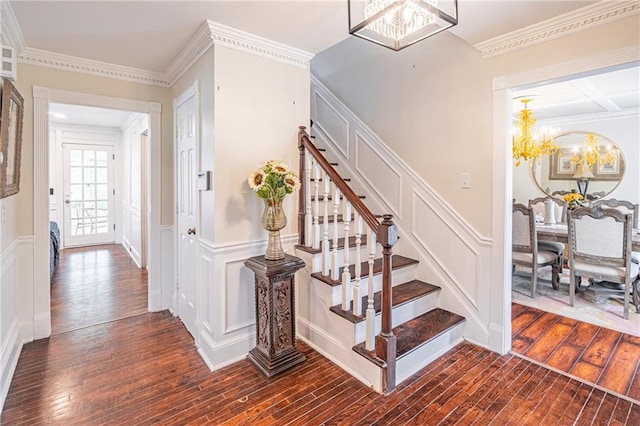 staircase featuring wood-type flooring, ornamental molding, and a chandelier