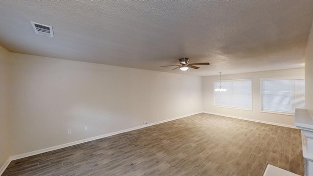 empty room with wood-type flooring, ceiling fan with notable chandelier, and a textured ceiling