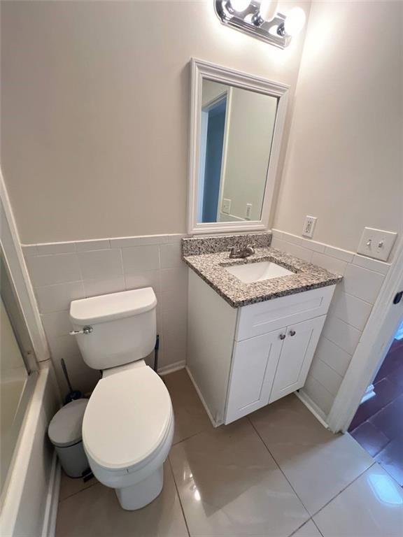 bathroom with tile walls, vanity, tile patterned flooring, and toilet