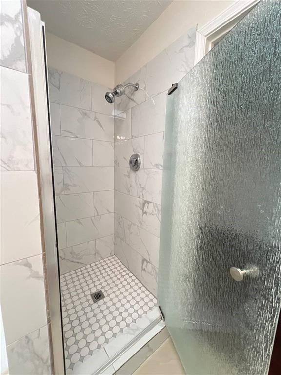 bathroom featuring tiled shower and a textured ceiling