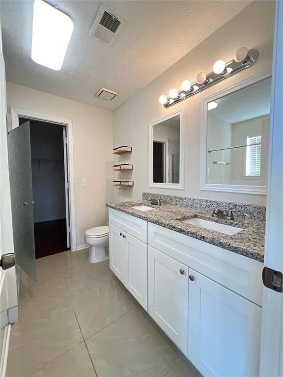 bathroom featuring a textured ceiling, toilet, and vanity