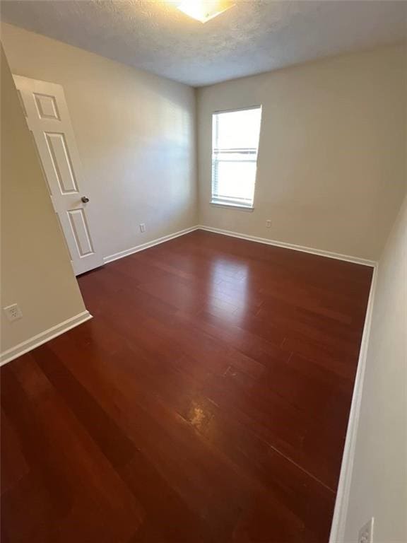 empty room featuring dark hardwood / wood-style floors and a textured ceiling