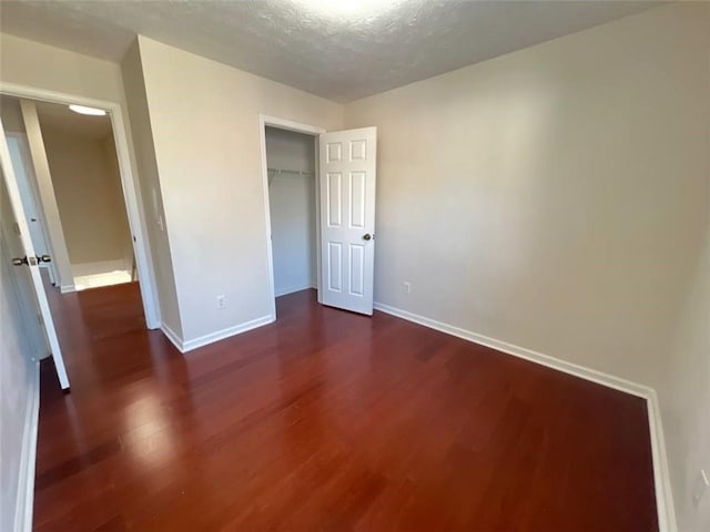 unfurnished bedroom featuring a textured ceiling, a closet, and dark hardwood / wood-style floors