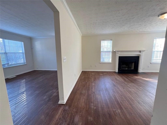 unfurnished living room with a textured ceiling, a wealth of natural light, crown molding, and dark hardwood / wood-style flooring