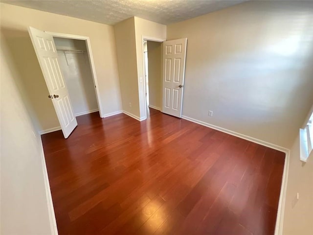 unfurnished bedroom with a closet, dark hardwood / wood-style flooring, and a textured ceiling