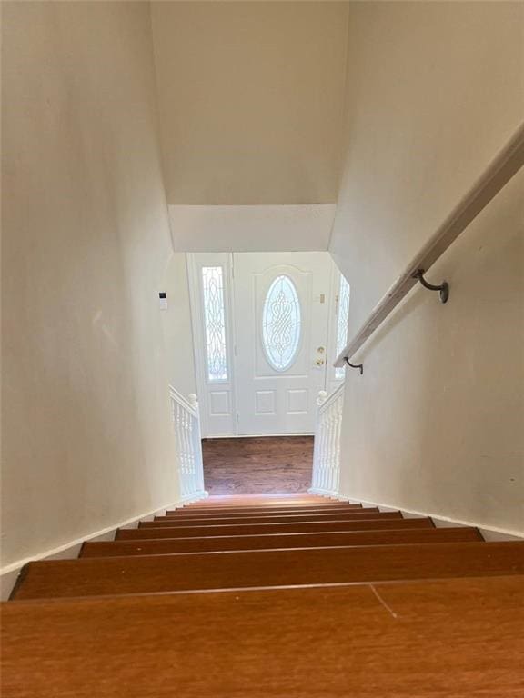 staircase featuring wood-type flooring and a high ceiling