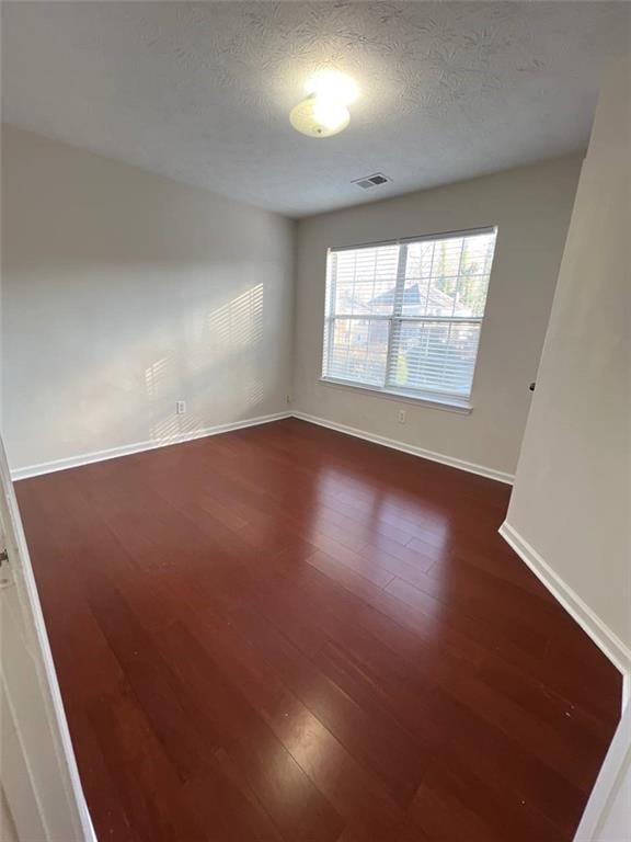 unfurnished room with a textured ceiling and dark hardwood / wood-style floors