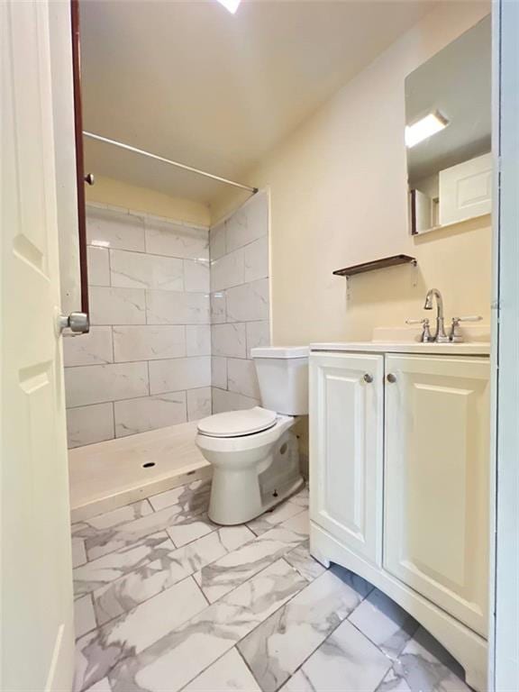 bathroom featuring vanity, tiled shower, and toilet