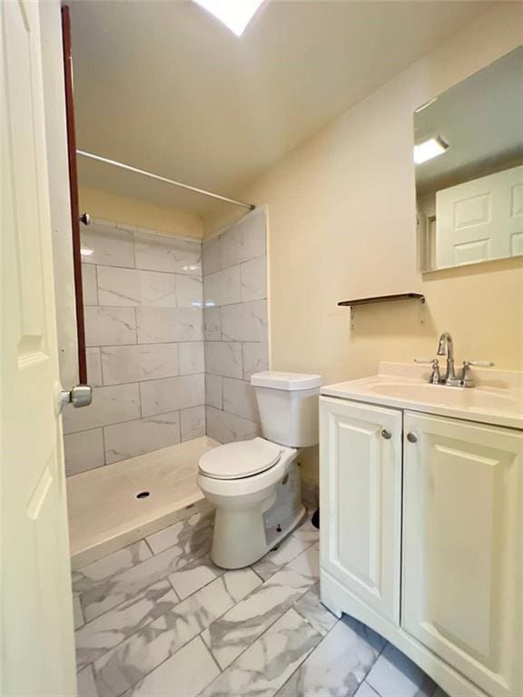 bathroom featuring toilet, a tile shower, and vanity