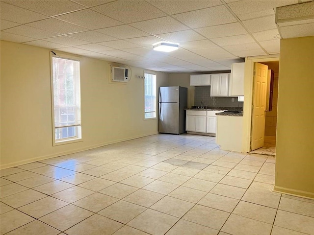 kitchen featuring white cabinets, a drop ceiling, stainless steel refrigerator, backsplash, and light tile patterned floors