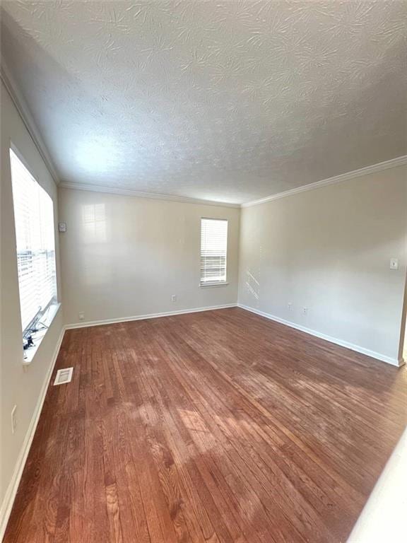 empty room with a textured ceiling, ornamental molding, and hardwood / wood-style flooring