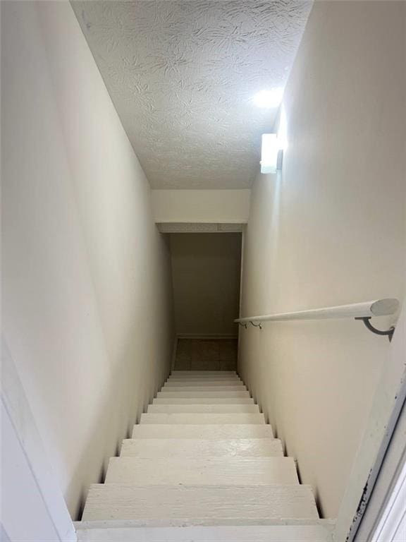 staircase featuring a textured ceiling