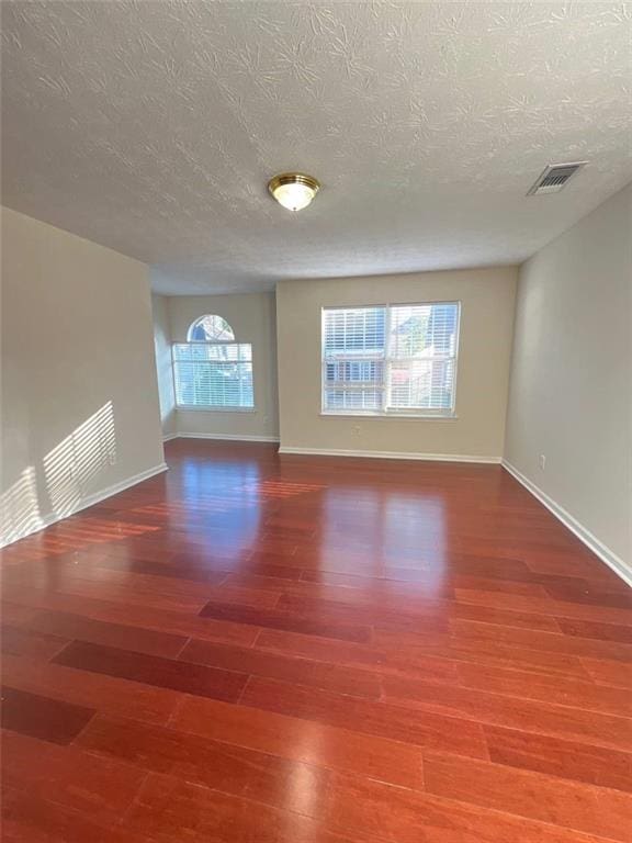 empty room featuring wood-type flooring and a textured ceiling