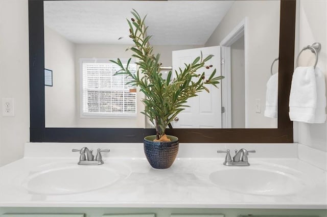 bathroom with a textured ceiling, double vanity, and a sink