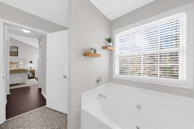 ensuite bathroom with lofted ceiling, a garden tub, and ensuite bathroom