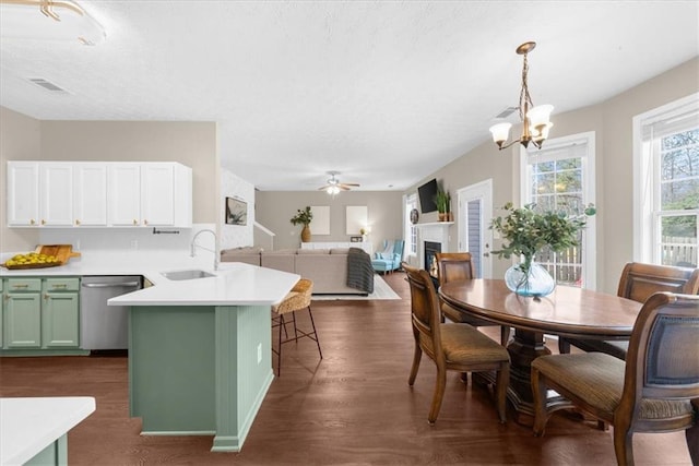 dining space with dark wood-style floors, ceiling fan with notable chandelier, a fireplace, and visible vents