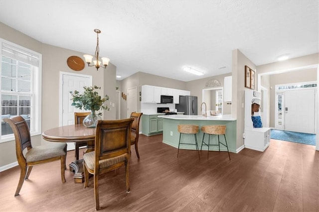 dining room featuring dark wood-type flooring, a notable chandelier, and baseboards