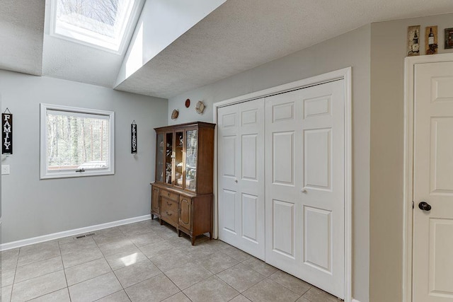 4434 Hidden Oaks Dr, Flowery Branch, GA 30542 - bedroom with light tile patterned floors, a textured ceiling, a skylight, and a closet