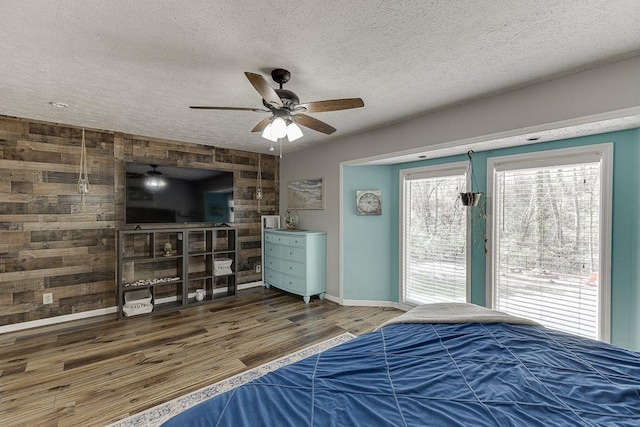 4434 Hidden Oaks Dr, Flowery Branch, GA 30542 - bedroom featuring wood finished floors, a textured ceiling, a ceiling fan, and wooden walls