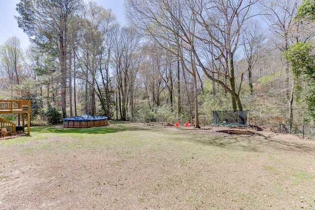 4434 Hidden Oaks Dr, Flowery Branch, GA 30542 - view of grassy yard featuring a trampoline, a covered pool, and a deck