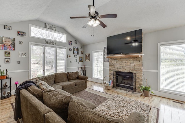 4434 Hidden Oaks Dr, Flowery Branch, GA 30542 - living area featuring a textured ceiling, ceiling fan, a stone fireplace, wood finished floors, and high vaulted ceiling