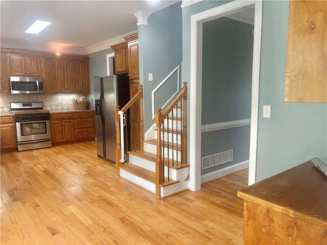 unfurnished living room featuring ornamental molding, a stone fireplace, hardwood / wood-style floors, and ceiling fan