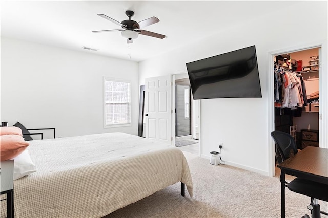 bedroom with a spacious closet, light carpet, ceiling fan, and a closet