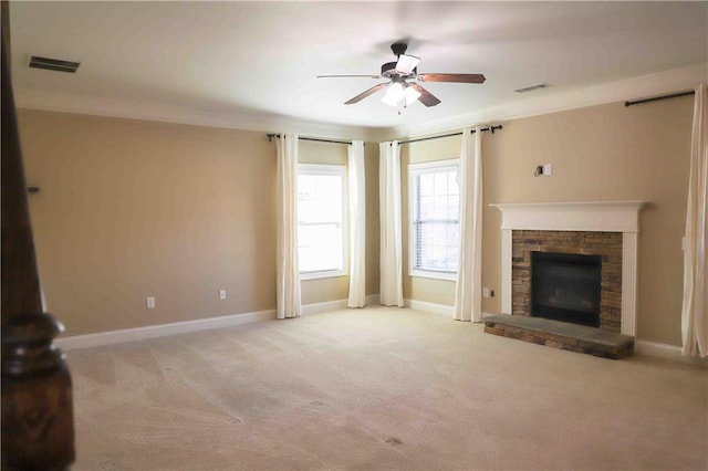 unfurnished living room featuring light carpet, a stone fireplace, ceiling fan, and crown molding