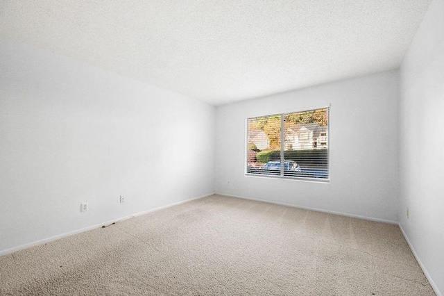 carpeted empty room featuring baseboards and a textured ceiling