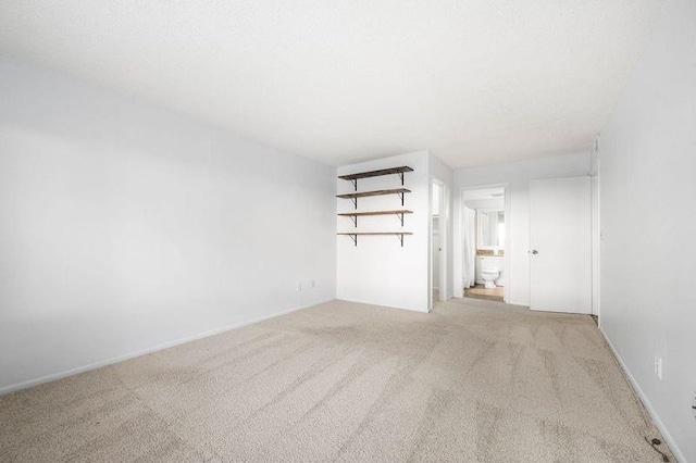 unfurnished bedroom featuring connected bathroom and light carpet