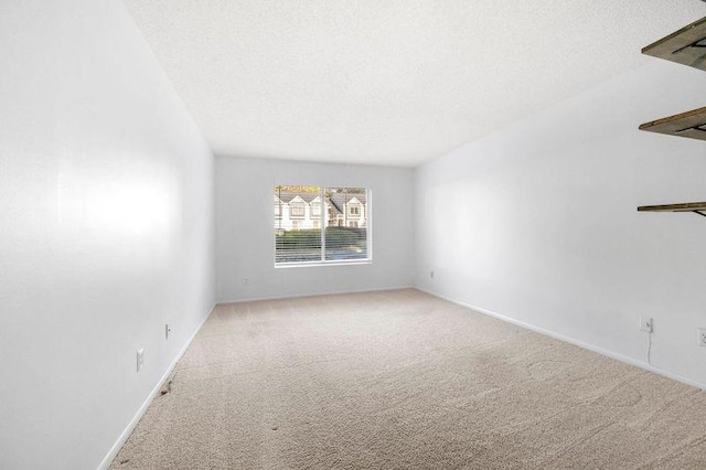 carpeted empty room with baseboards and a textured ceiling