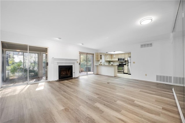 unfurnished living room with a fireplace with flush hearth, light wood-style floors, visible vents, and baseboards