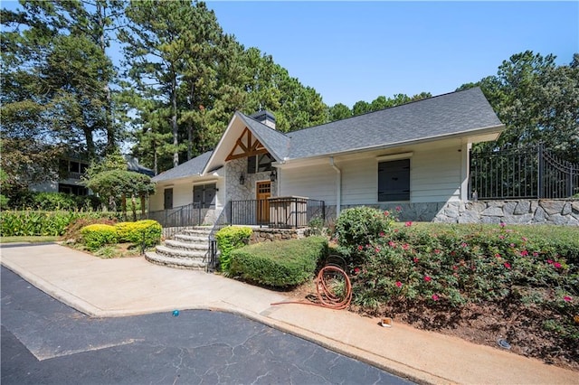 view of front of property featuring stone siding, roof with shingles, and a chimney