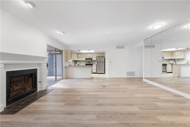 unfurnished living room with light wood finished floors, a fireplace with flush hearth, and visible vents