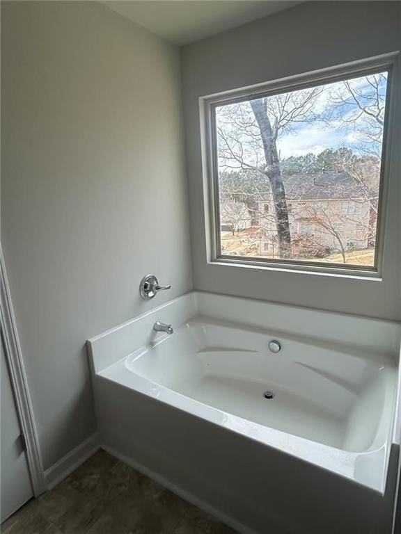 full bath featuring baseboards and a bath