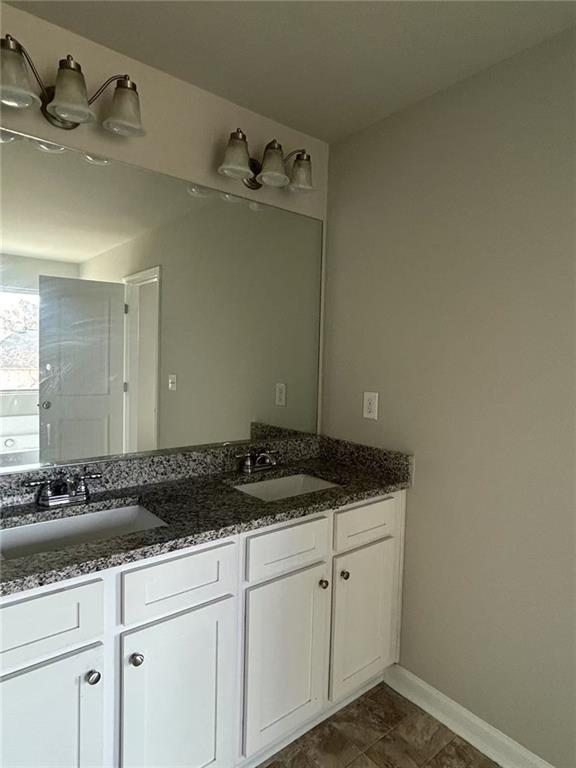 bathroom featuring double vanity, a sink, and baseboards