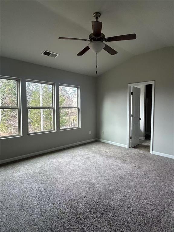 carpeted spare room featuring lofted ceiling, baseboards, visible vents, and a ceiling fan