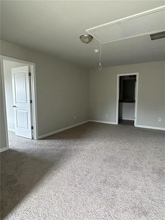 empty room with visible vents, carpet floors, attic access, and baseboards