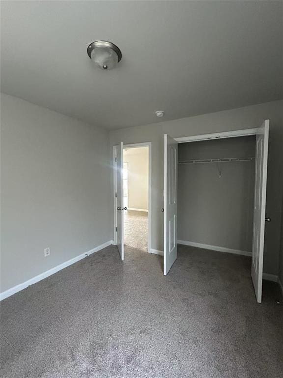 unfurnished bedroom with carpet, a closet, and baseboards