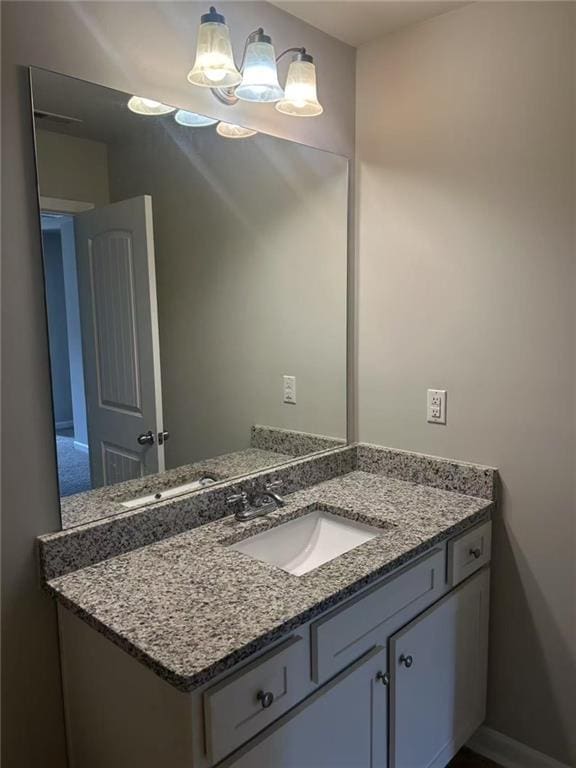 bathroom with a notable chandelier, vanity, and baseboards