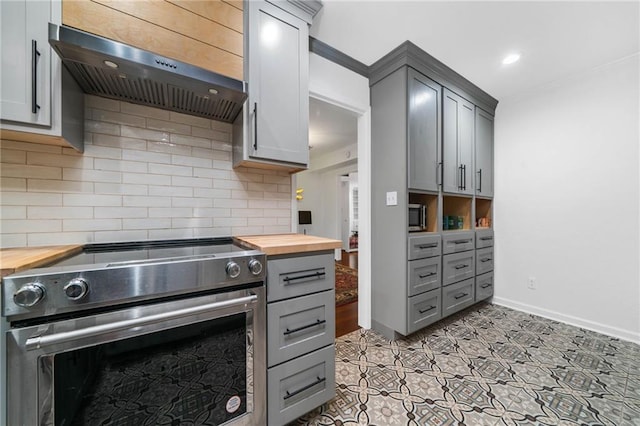kitchen featuring wood counters, appliances with stainless steel finishes, exhaust hood, gray cabinetry, and recessed lighting